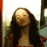 a woman with long hair standing in front of a mirror